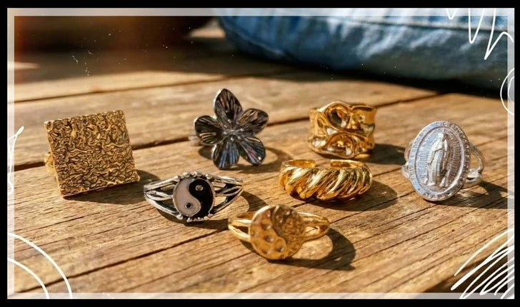 Zinc alloy fashion rings with flower, yin yang and textured gold designs on wood
