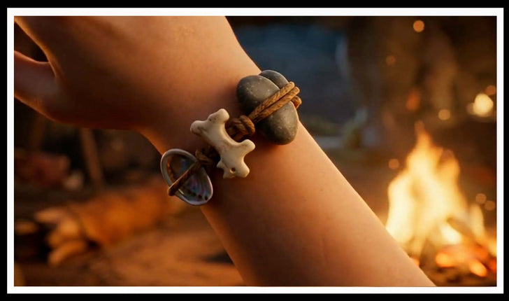 Wrist wearing a bone, shell and stone cord bracelet by a campfire