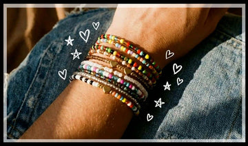 Wrist stacked with colourful seed bead bracelets and gold hearts