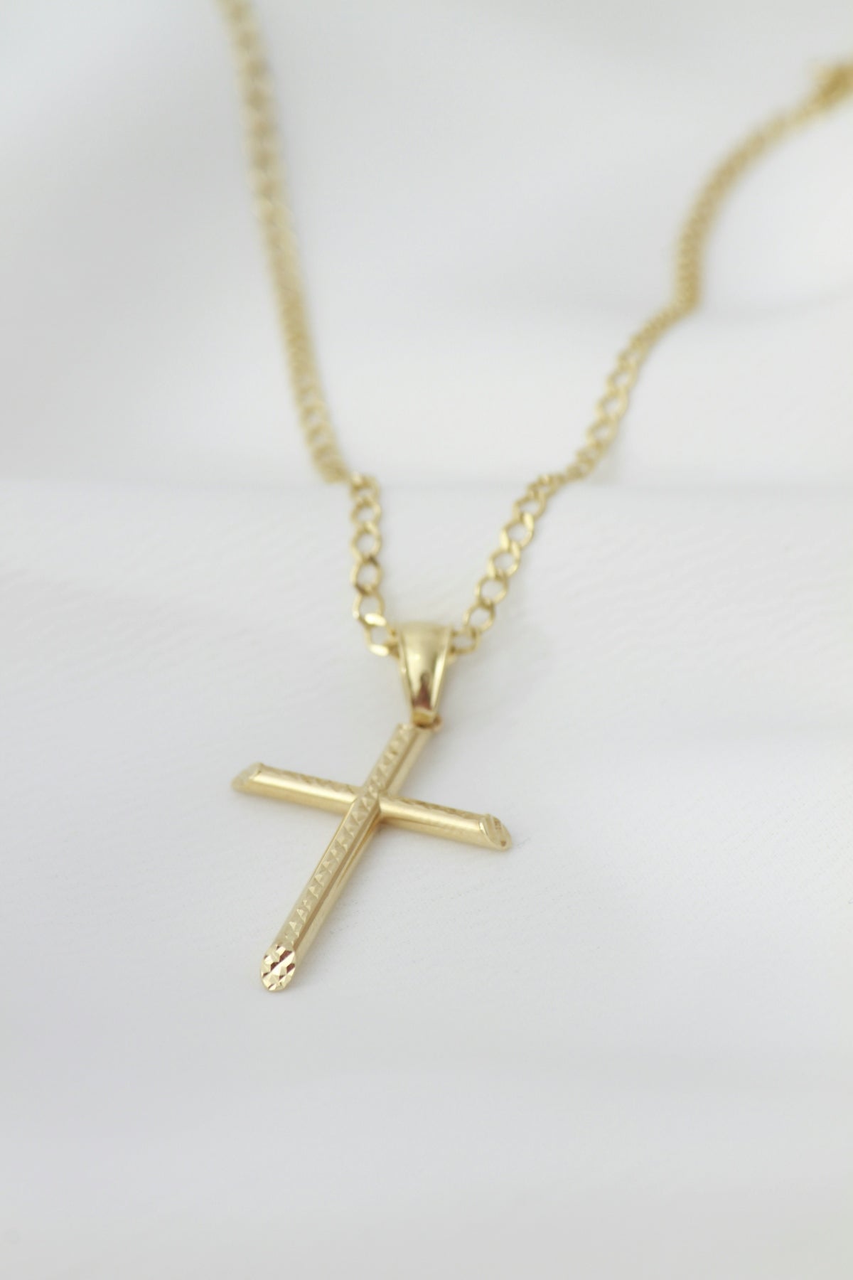 A gold necklace with a cross on it
