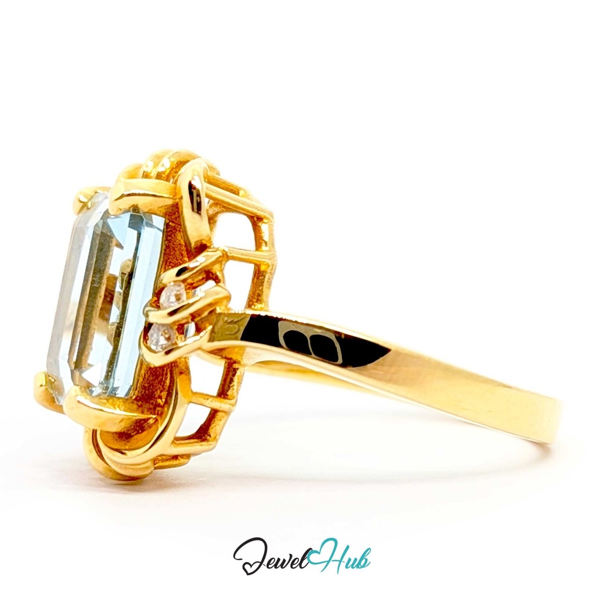 A 14k yellow gold ring featuring a large rectangular emerald-cut light blue gemstone and a small round accent stone, shown on a white background with a 'JewelHub' watermark.