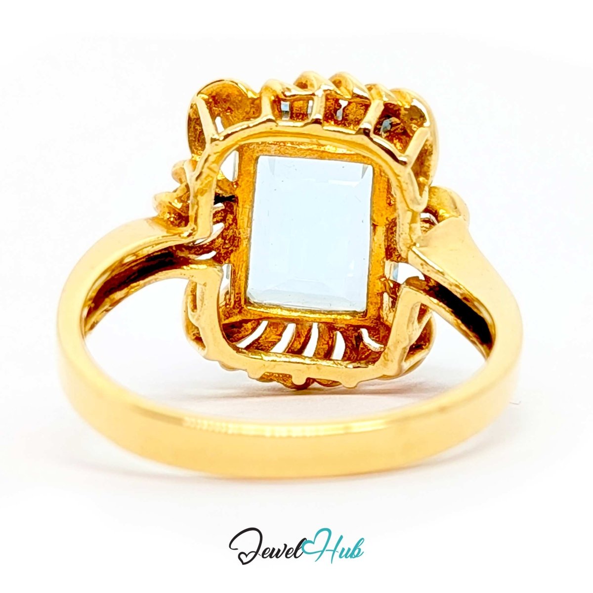 A 14k gold ring featuring a rectangular light blue gemstone in an ornate filigree setting, shown on a white background with a 'JewelHub' watermark at the bottom.