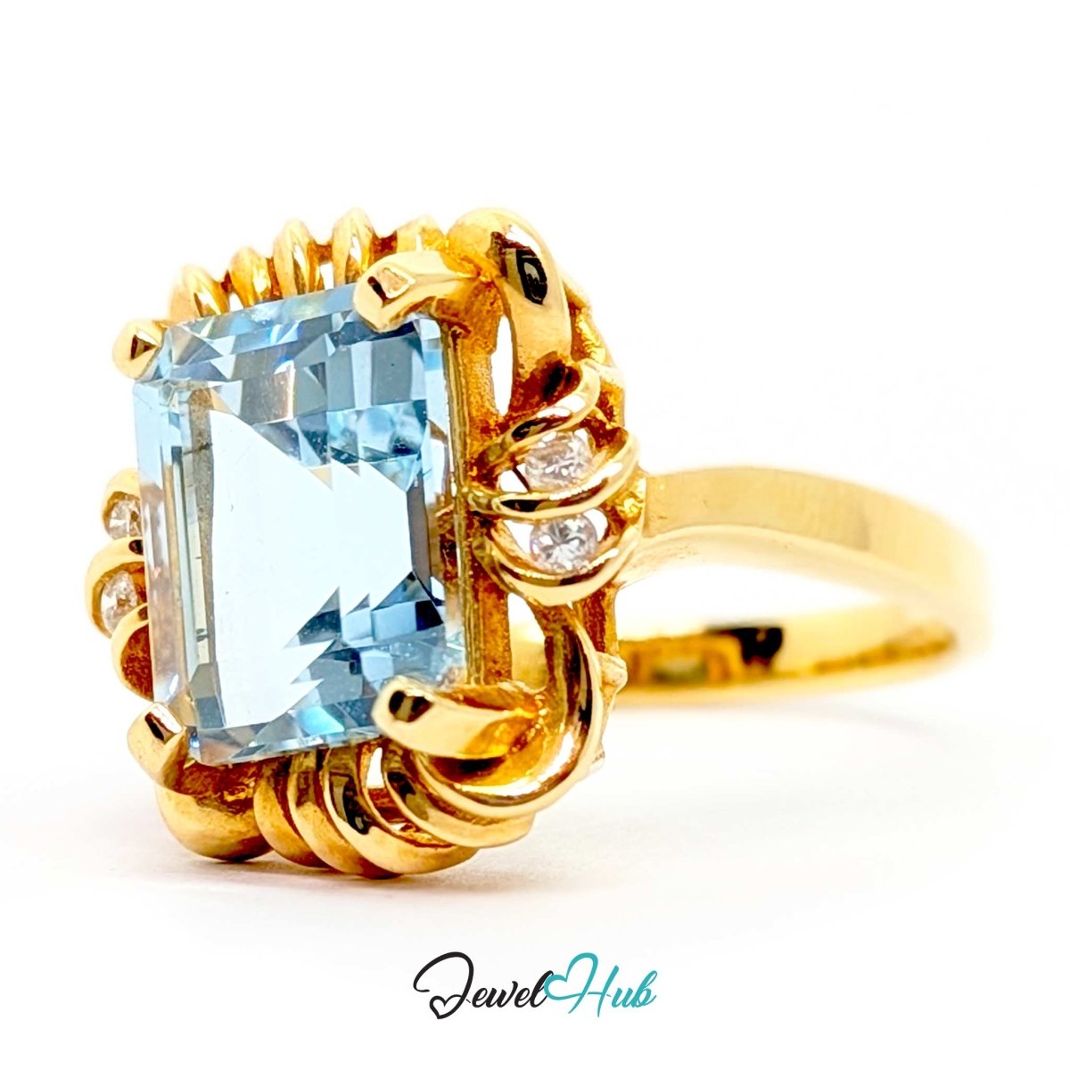 A 14k yellow gold ring featuring a large rectangular light blue gemstone and small accent stones, shown on a white background with a JewelHub watermark.