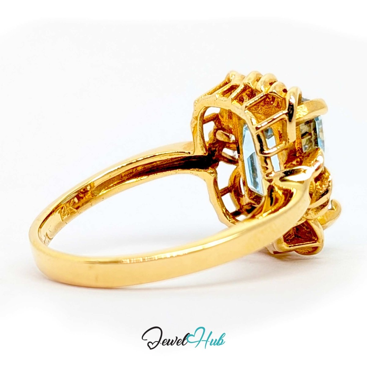 A 14k yellow gold ring with a large, intricate openwork setting holding light blue gemstones, shown on a white background with a 'JewelHub' watermark at the bottom.