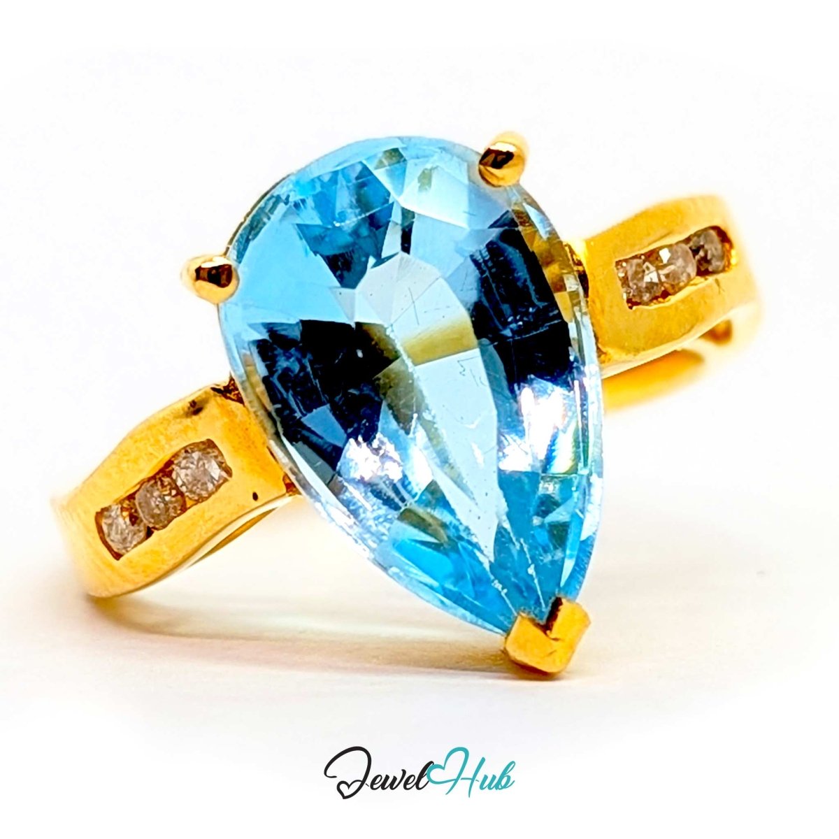 A 14k gold ring featuring a large, faceted pear-cut light blue gemstone in a prong setting, with small clear accent stones on the shoulders, shown on a white background with a 'JewelHub' watermark.
