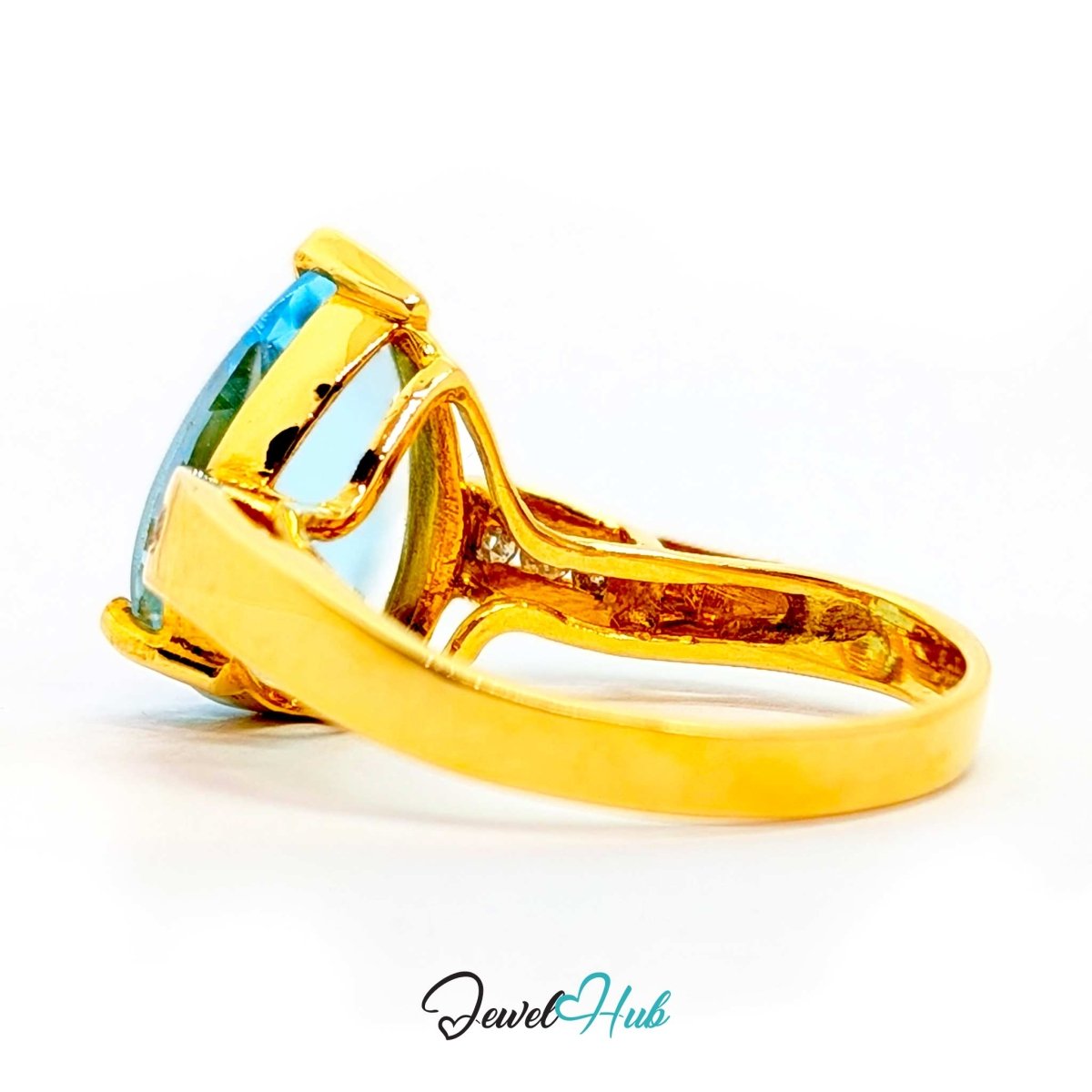 A 14k yellow gold ring featuring a large, cushion-cut light blue gemstone in a prong setting, shown on a clean white background with a 'JewelHub' watermark at the bottom.