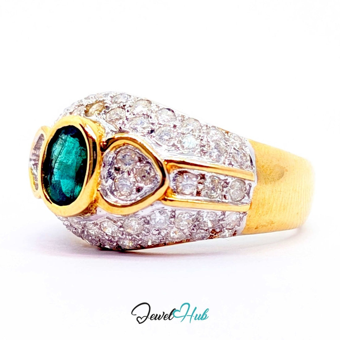 A 14k yellow gold ring featuring a central oval emerald green gemstone, flanked by two heart-shaped clear stones and a small round accent stone, all set in a pavé setting of clear stones. The ring is photographed on a white background with a 'JewelHub' watermark at the bottom.