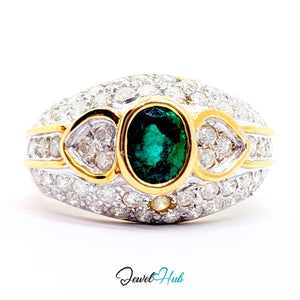 A 14k yellow gold ring featuring a central oval emerald green gemstone, flanked by two heart-shaped clear stones and a small round accent stone, all set in a pavé setting of clear stones. The ring is photographed on a white background with a 'JewelHub' watermark at the bottom.