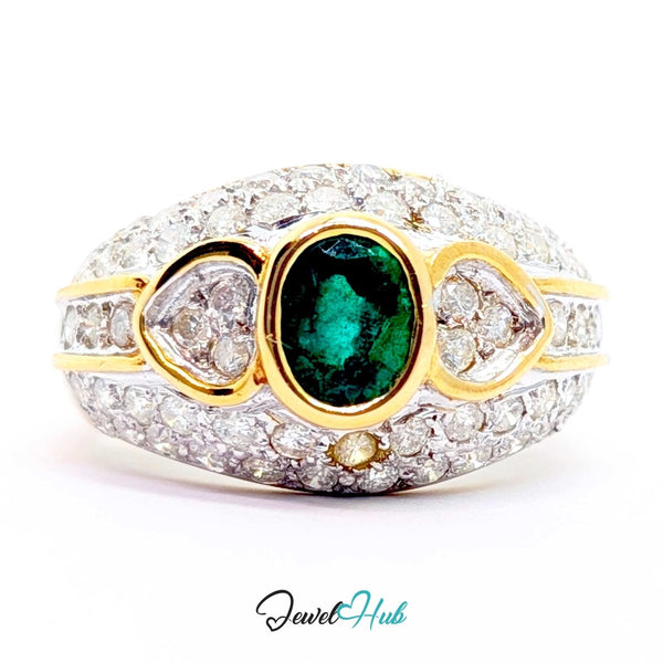A 14k yellow gold ring featuring a central oval emerald green gemstone, flanked by two heart-shaped clear stones and a small round accent stone, all set in a pavé setting of clear stones. The ring is photographed on a white background with a 'JewelHub' watermark at the bottom.