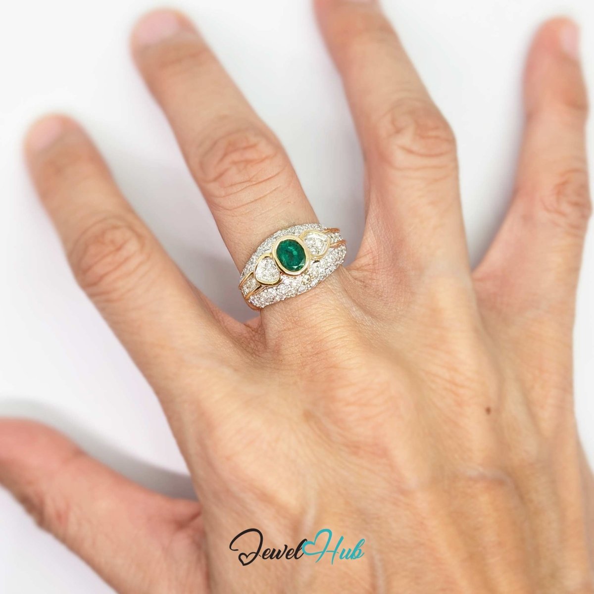 A close-up of a hand wearing a 14k gold ring with a central oval green emerald and pavé-set stones, on a plain white background.