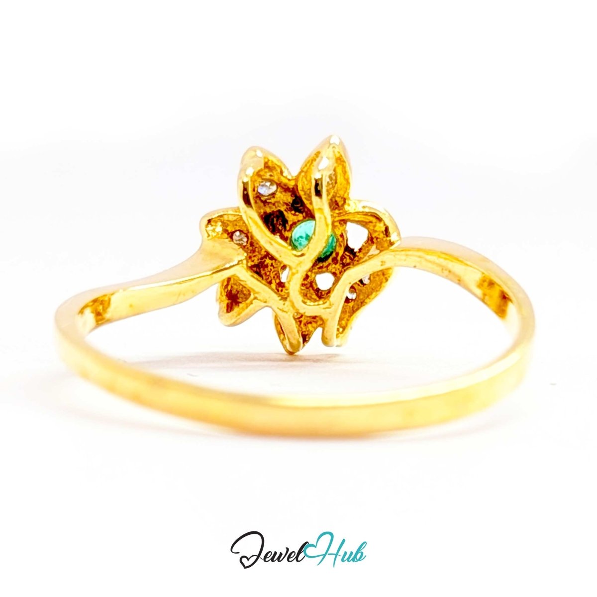 A yellow 14k gold ring featuring a stylized flower setting with a small green oval stone in the center and tiny clear accent stones, shown on a white background with a 'JewelHub' watermark at the bottom.