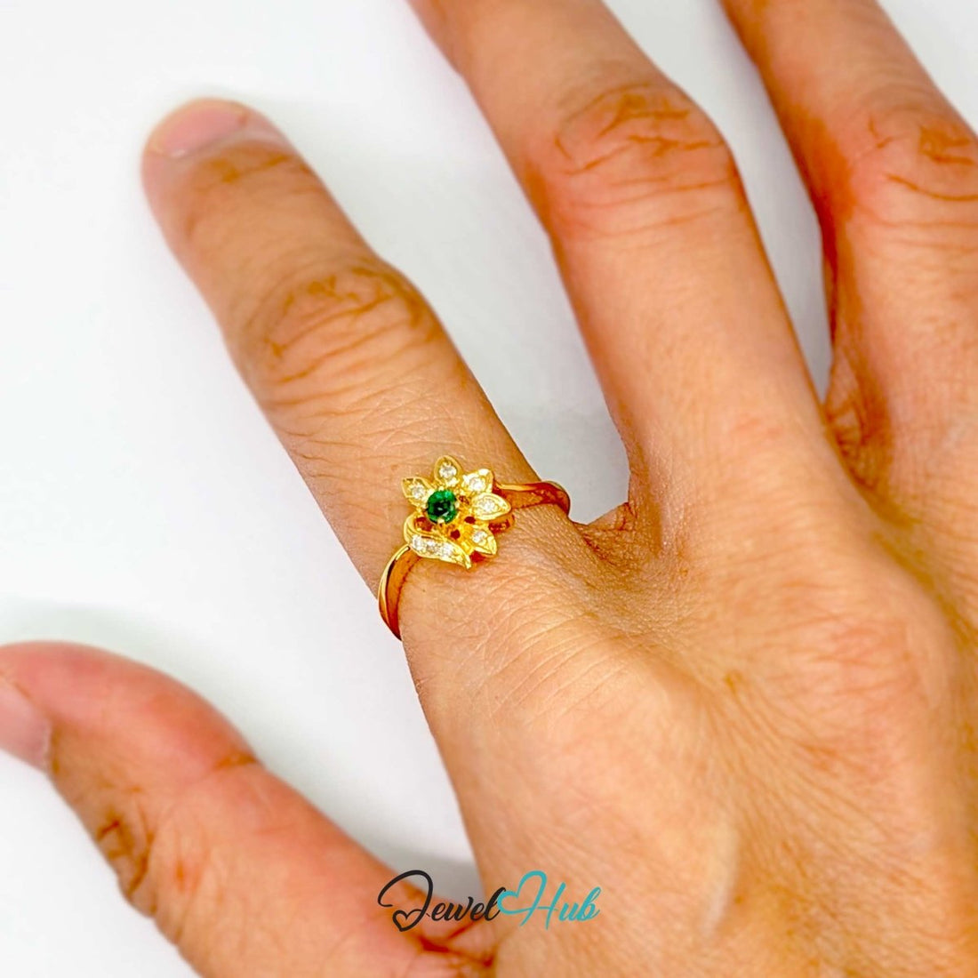 A yellow 14k gold flower-shaped ring featuring a central round green emerald-cut gemstone and multiple small round-cut diamonds set in petal-like shapes, shown on a white background with a JewelHub watermark.