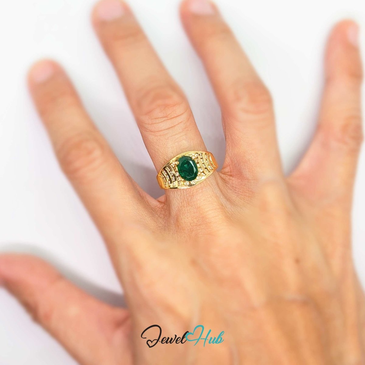 A gold 14kring with a green oval gemstone and small clear stones, shown worn on a person's finger against a plain white background.