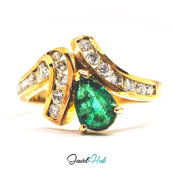A 14k gold ring featuring a large pear-cut green emerald center stone and curved gold bands set with small clear stones, shown on a white background with a JewelHub watermark.