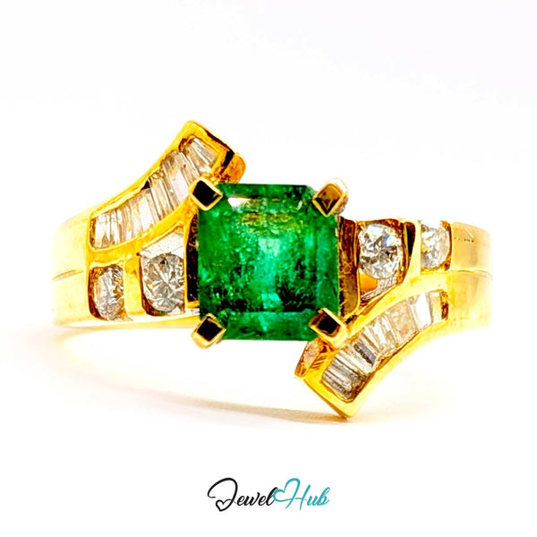 A 14k yellow gold ring featuring a rectangular green emerald-cut center stone and baguette-cut clear stones on curved side bands, shown on a white background with a JewelHub watermark.