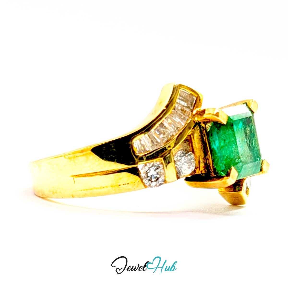 A 14k yellow gold ring featuring a rectangular green emerald-cut center stone and small clear baguette and round diamonds on the shoulders, shown on a white background with a JewelryHub watermark.