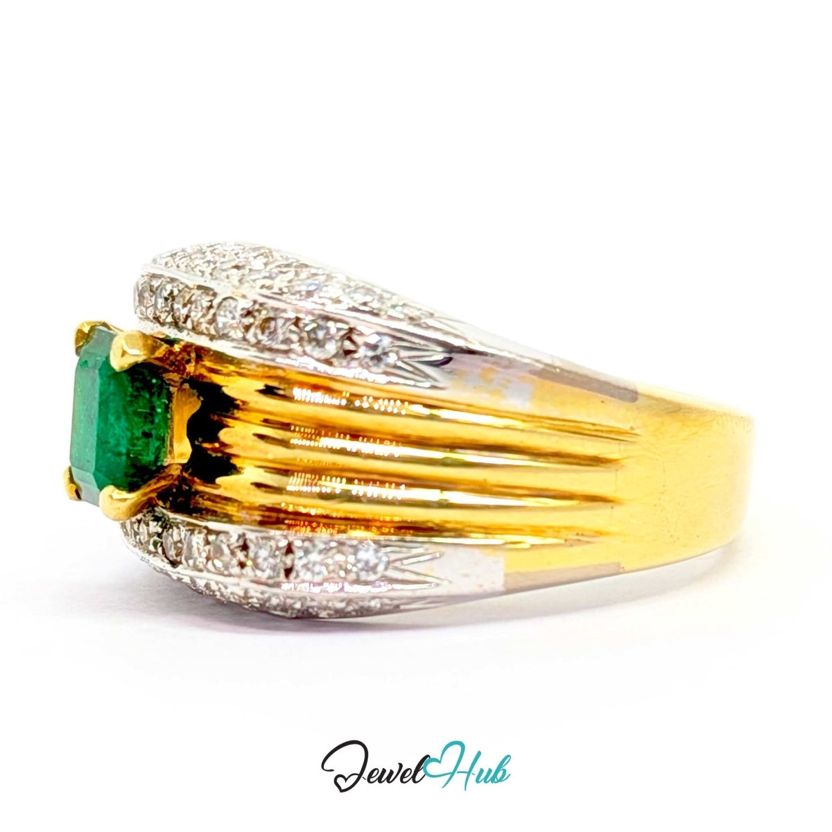 A yellow 14k gold ring featuring a rectangular green emerald-cut center stone, surrounded by pavé-set clear stones and a split shank design with silver-colored accents, shown on a white background with a JewelryHub watermark.