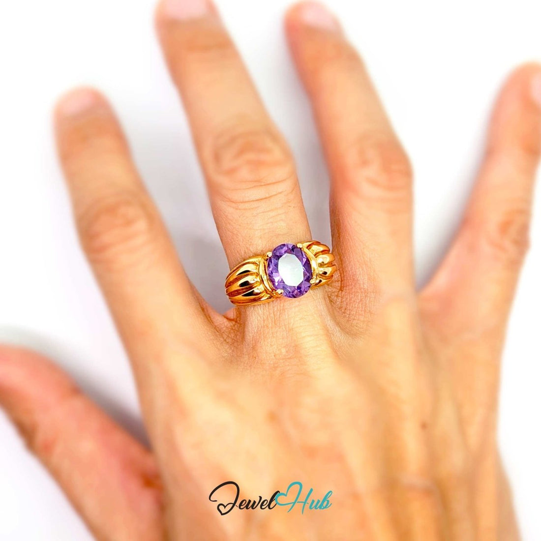A yellow 14k gold ring featuring a large oval-cut purple amethyst gemstone in a prong setting, with a textured, ribbed gold band. The ring is photographed on a clean white background with a 'JewelHub' watermark at the bottom.