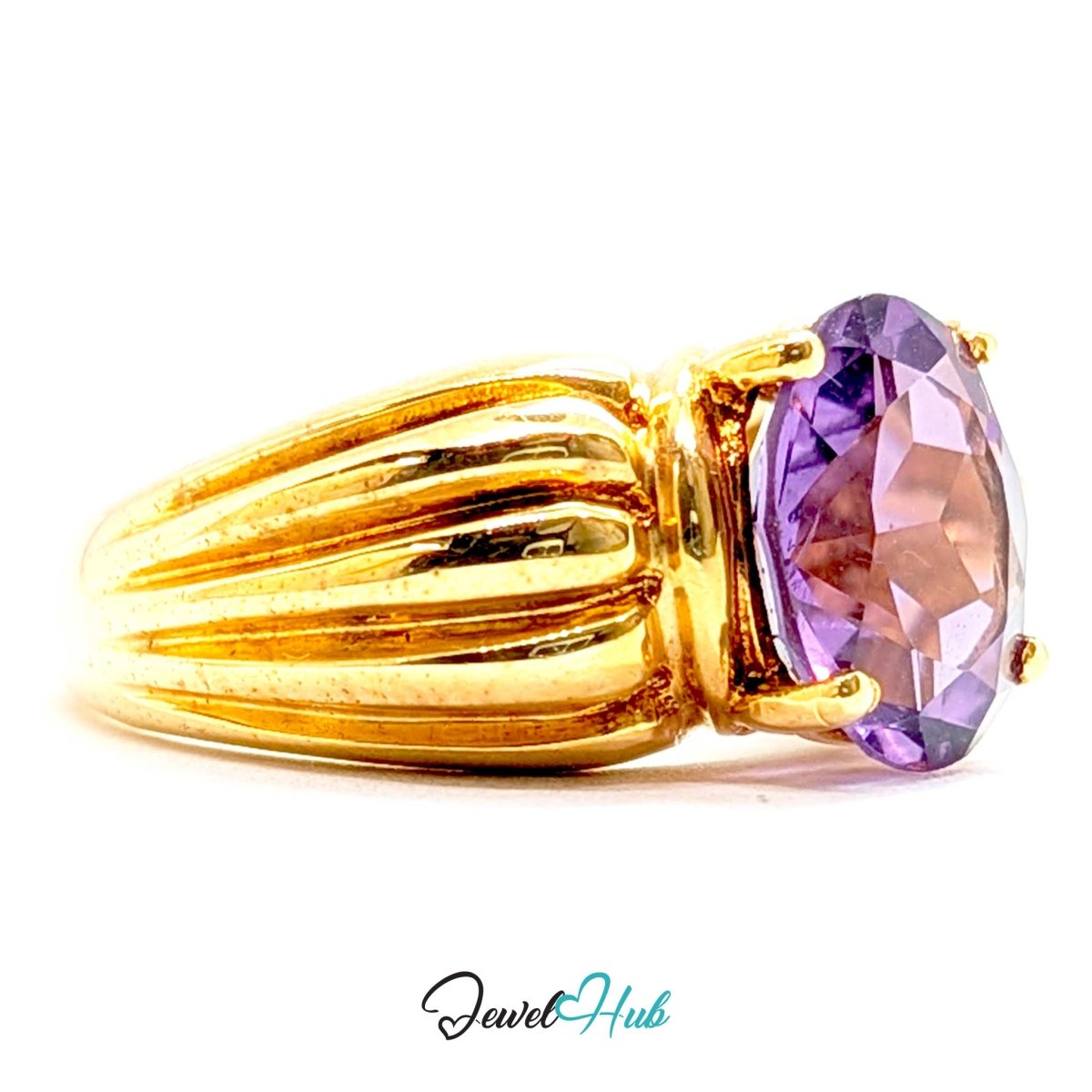 A 14k yellow gold ring featuring a large oval-cut purple amethyst gemstone in a prong setting, with a textured, ribbed gold band. The ring is photographed on a clean white background with a 'JewelHub' watermark at the bottom.