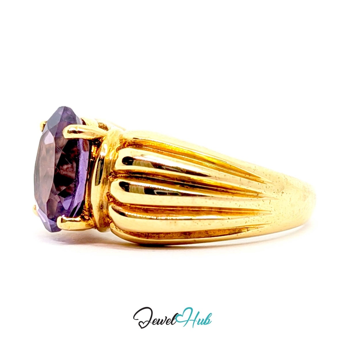 A 14k gold ring featuring a large oval-cut purple gemstone in a prong setting, with a fluted gold band, shown against a plain white background.