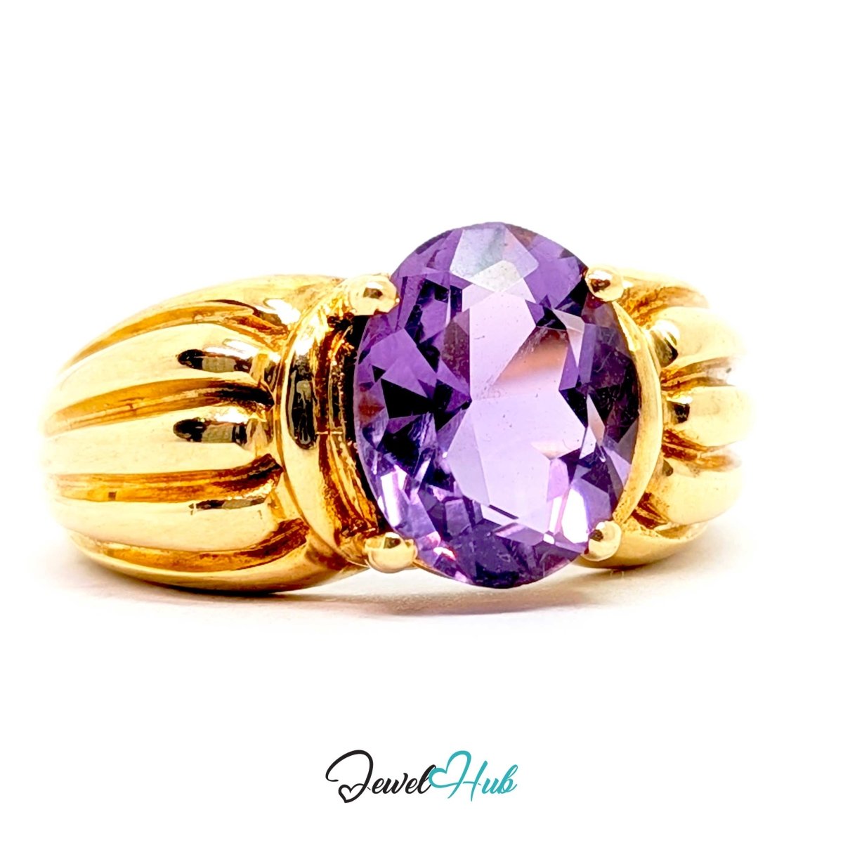 A 14k yellow gold ring featuring a large, oval-cut faceted purple amethyst gemstone in a prong setting, with decorative ribbed gold sides, shown on a white background with a 'JewelHub' watermark.