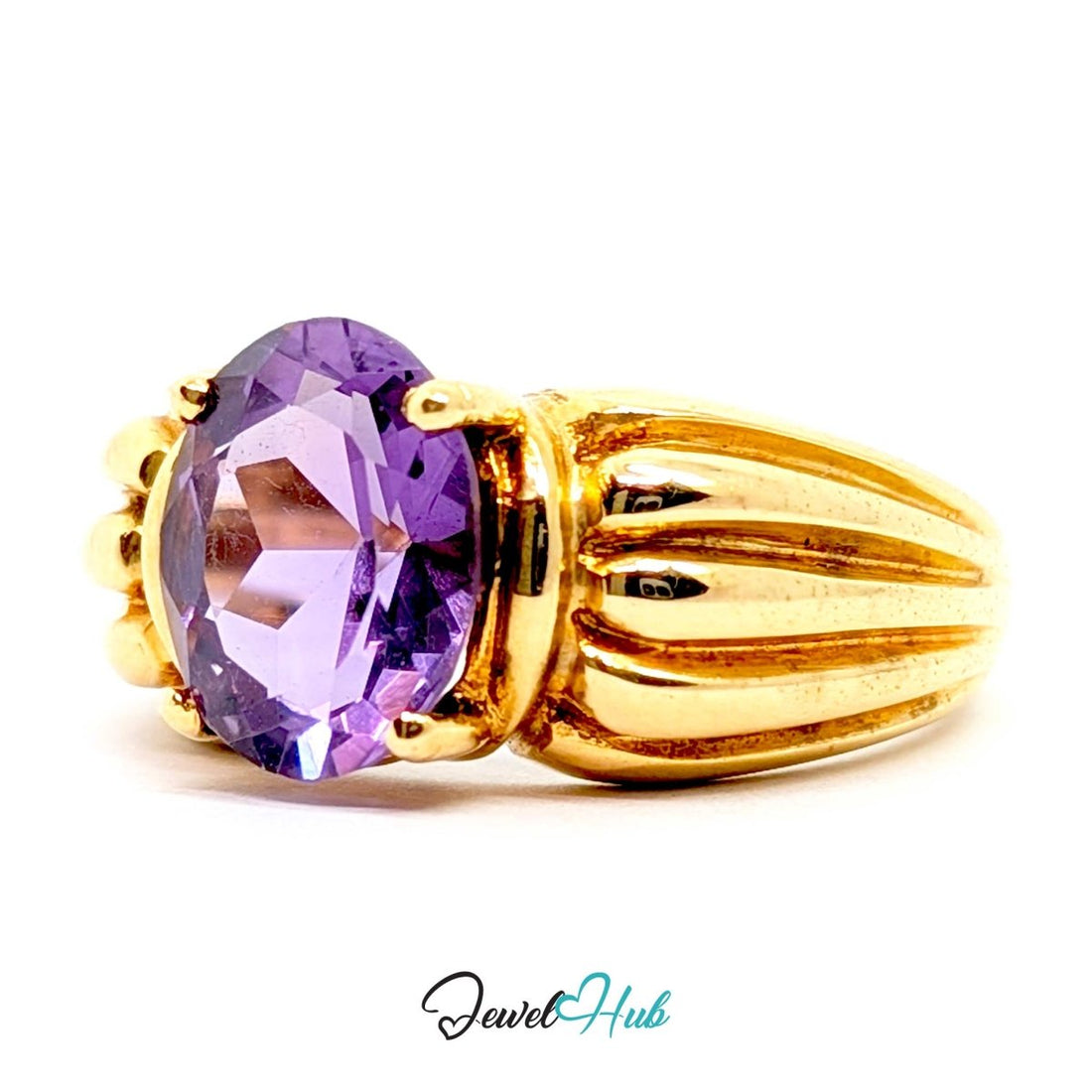 A yellow 14k gold ring featuring a large oval-cut purple amethyst gemstone in a prong setting, with a textured, ribbed gold band. The ring is photographed on a clean white background with a 'JewelHub' watermark at the bottom.