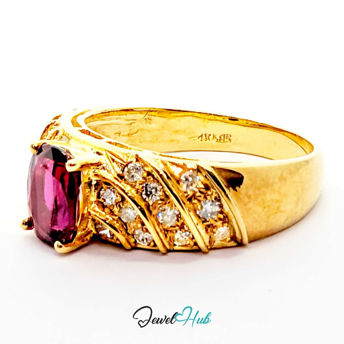 A yellow 14k gold ring featuring a large oval-cut pink gemstone in the center, surrounded by smaller clear stones and textured gold bands, shown on a white background with a JewelryHub watermark.