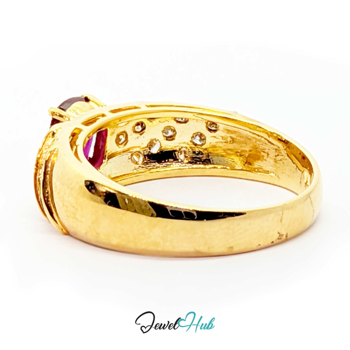 A yellow 14k gold ring with a curved band, featuring a dark red gemstone on one end, a row of small clear stones on the inner band, and a polished finish. The ring is photographed on a white background with a 'JewelHub' watermark at the bottom.