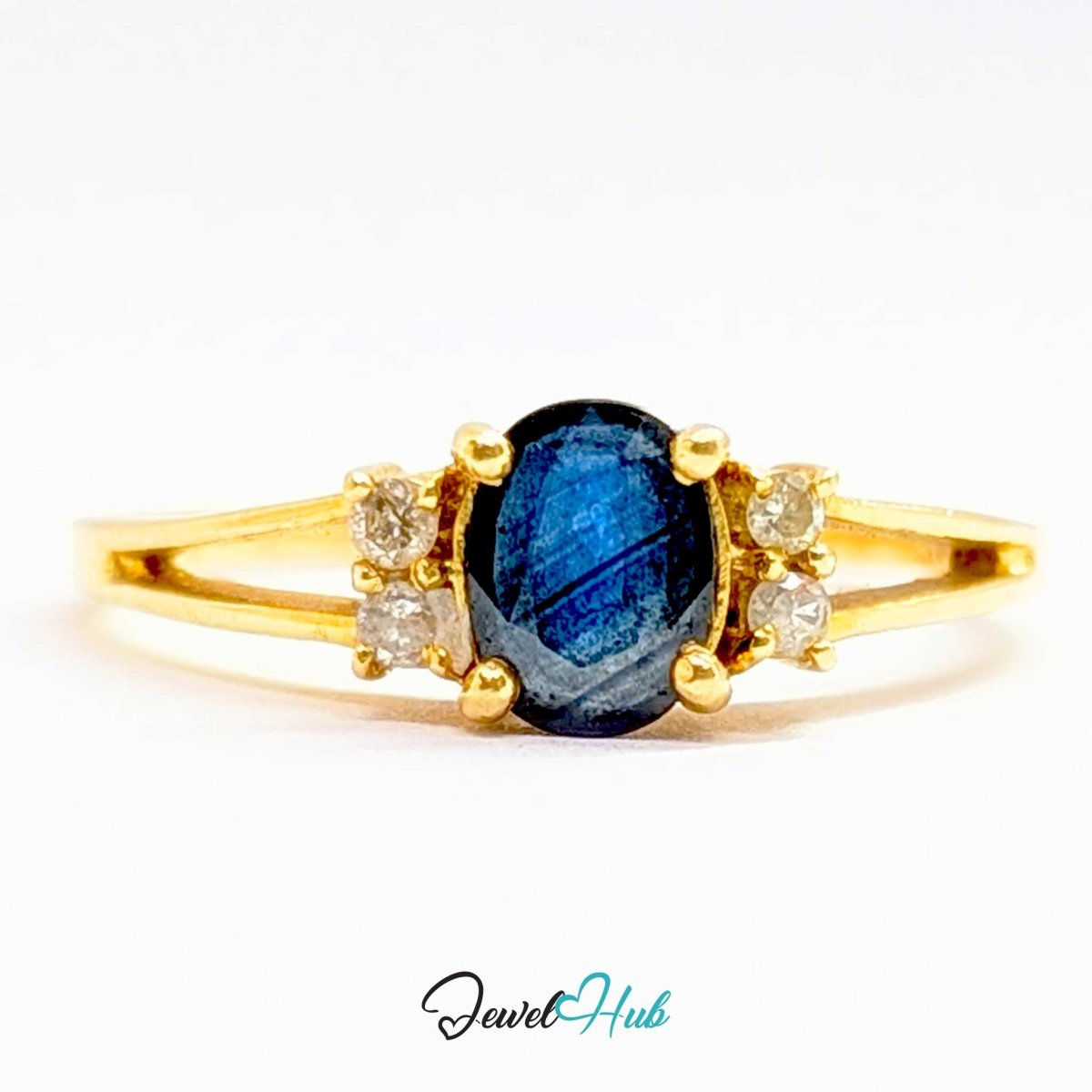 A 14k yellow gold ring featuring a central oval-cut deep blue labradorite gemstone, flanked by three small round clear accent stones on each side, set against a plain white background with a 'JewelHub' watermark at the bottom.