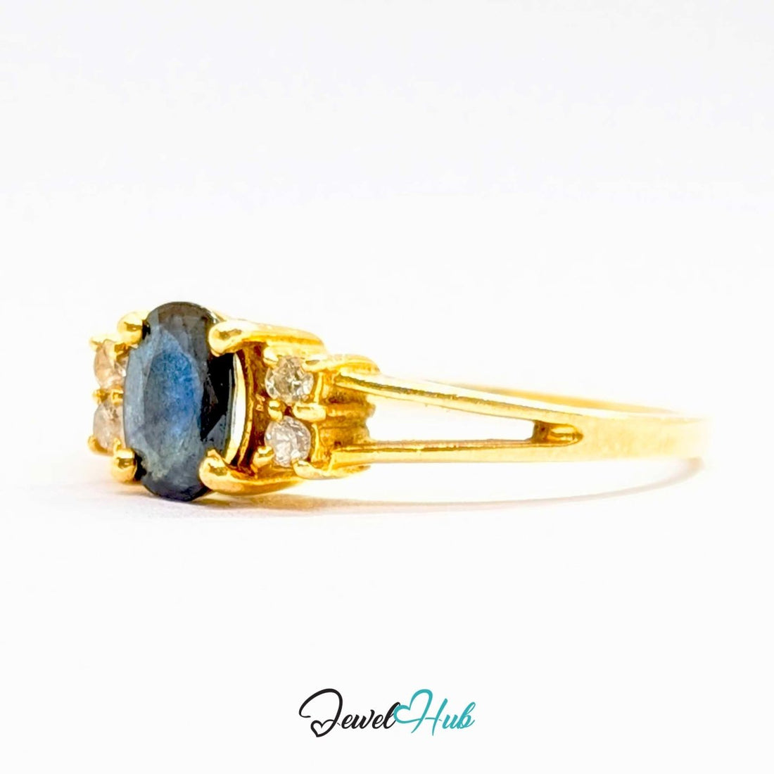A yellow 14k gold ring featuring a central oval-cut deep blue labradorite gemstone, flanked by two small round-cut clear accent stones on each side. The ring is photographed on a clean white background with a 'JewelHub' watermark at the bottom.