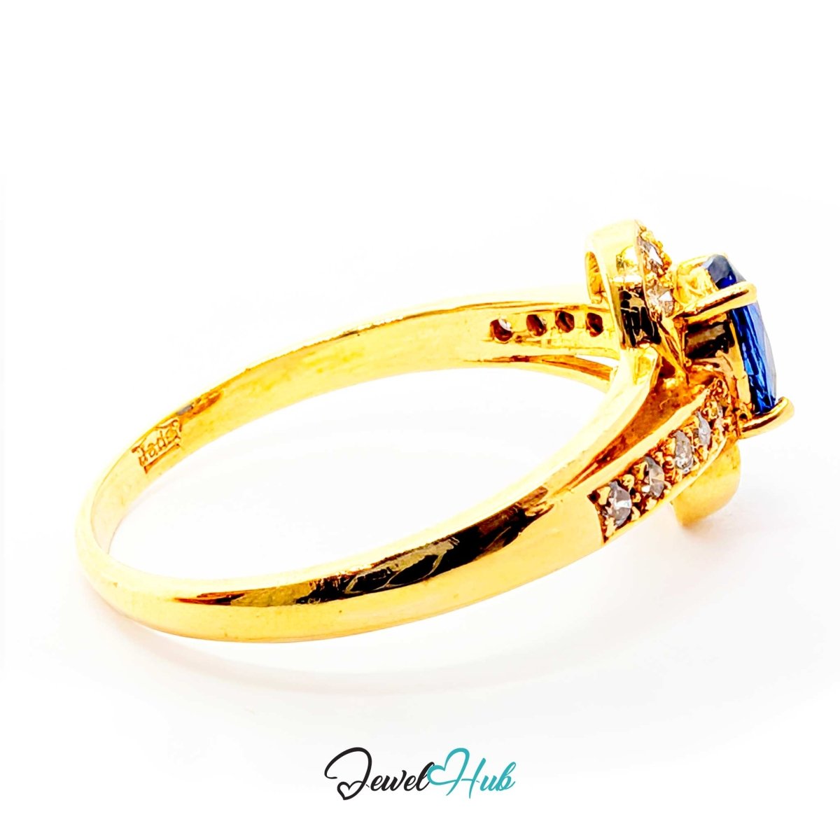 A 14k yellow gold ring featuring a marquise-cut blue sapphire and small clear accent stones, shown on a white background with a 'JewelHub' watermark at the bottom.