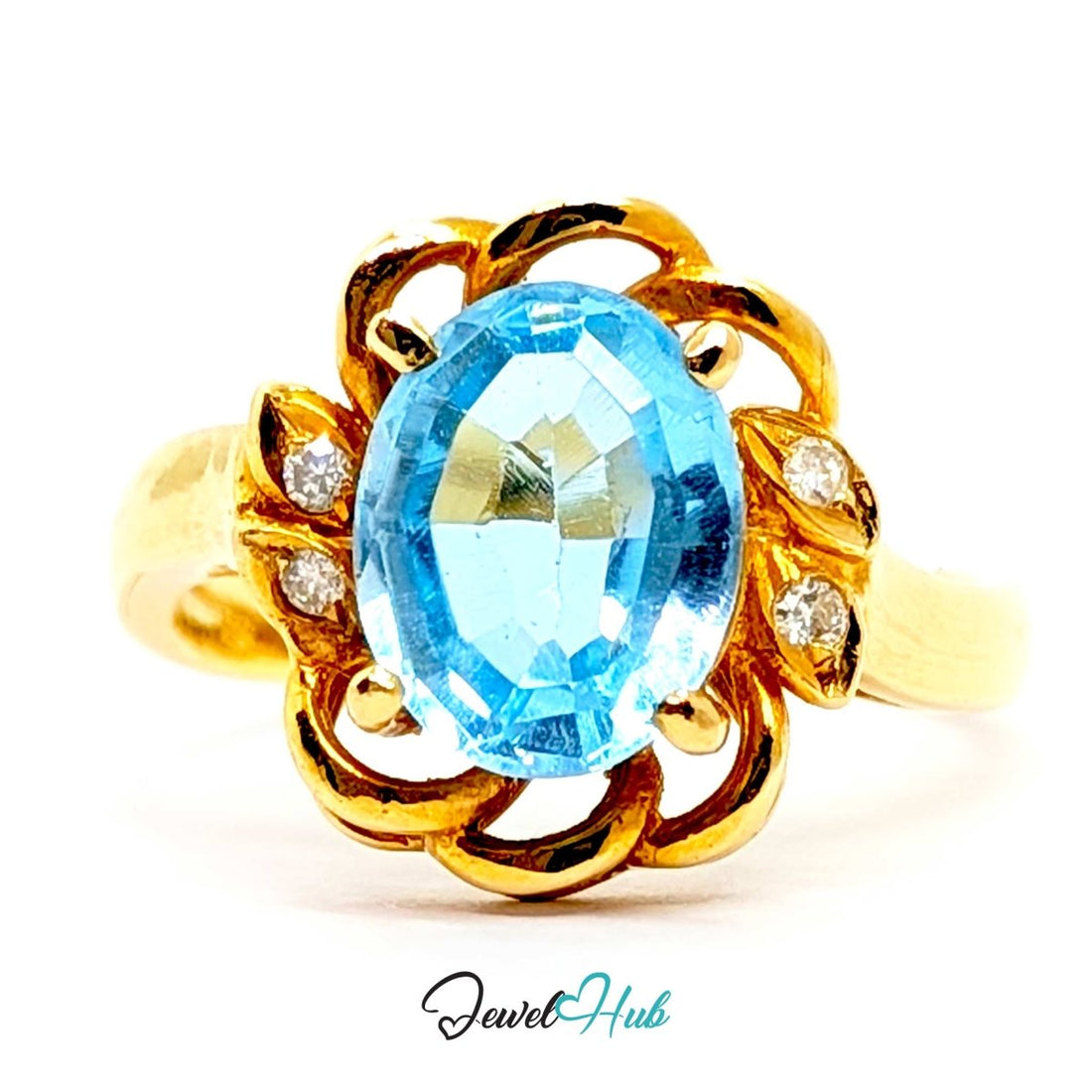 A yellow 14k gold ring featuring an oval-cut light blue topaz center stone and small round diamond accents on the sides, set against a plain white background with a 'JewelHub' watermark at the bottom.