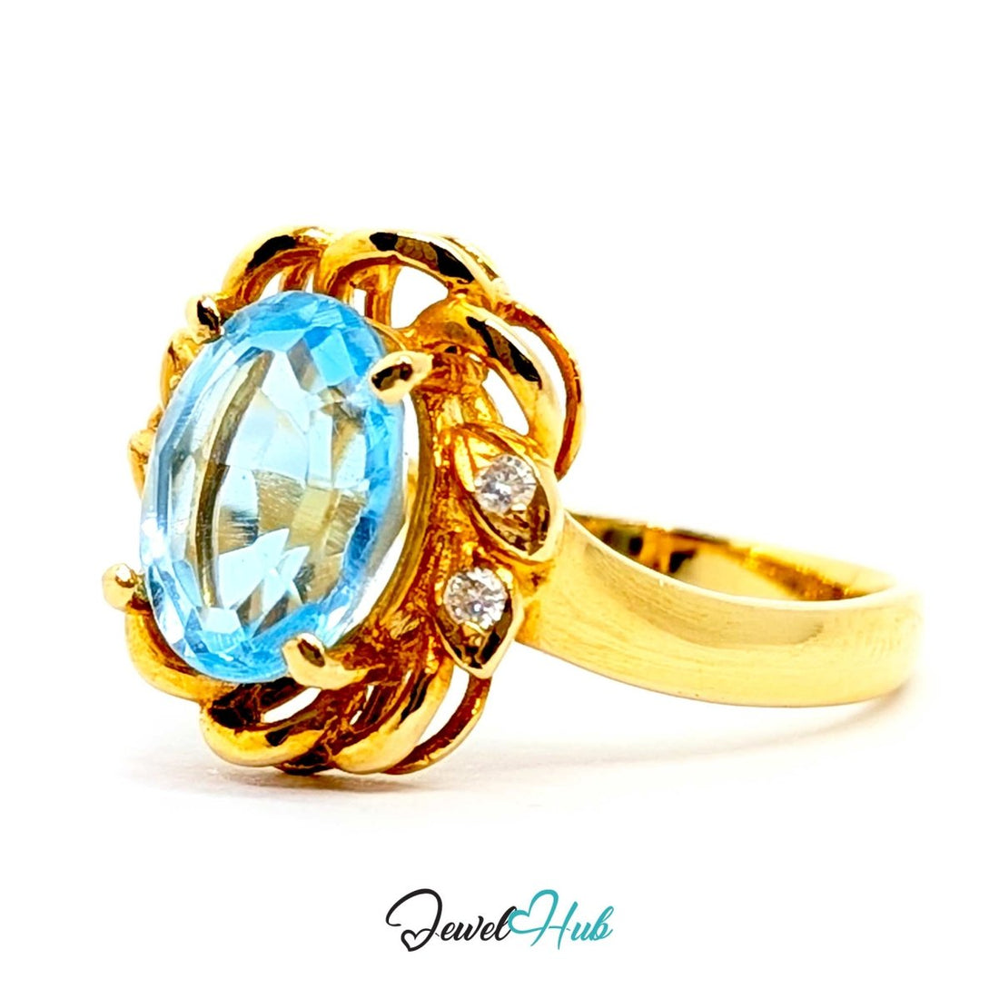 A yellow 14k gold ring featuring an oval-cut light blue topaz center stone and small round diamond accents on the sides, set against a plain white background with a 'JewelHub' watermark at the bottom.