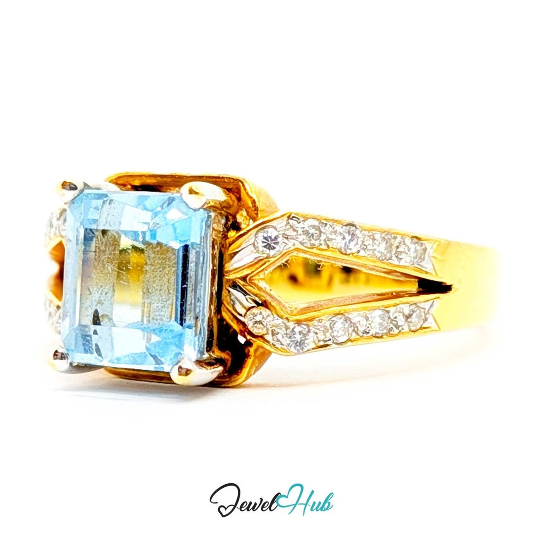 A 18k yellow gold ring featuring a large rectangular emerald-cut light blue gemstone in the center, flanked by pavé-set clear stones on the band and a gold setting.
