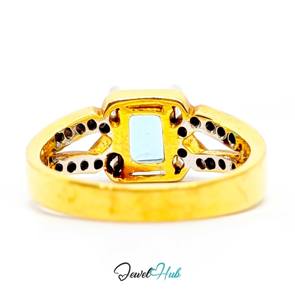 A 18k gold ring with a rectangular light blue gemstone in the center, surrounded by small black dot accents on a white background.
