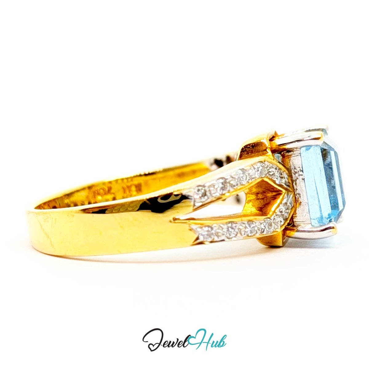 A 18k yellow gold ring with a split shank featuring small pavé diamonds and a rectangular light blue gemstone, shown on a white background with a 'JewelHub' watermark.