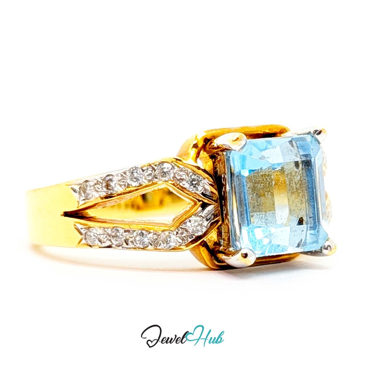 A 18k yellow gold ring featuring a large rectangular light blue gemstone and a diamond-accented split shank, shown on a white background with a 'JewelHub' watermark.