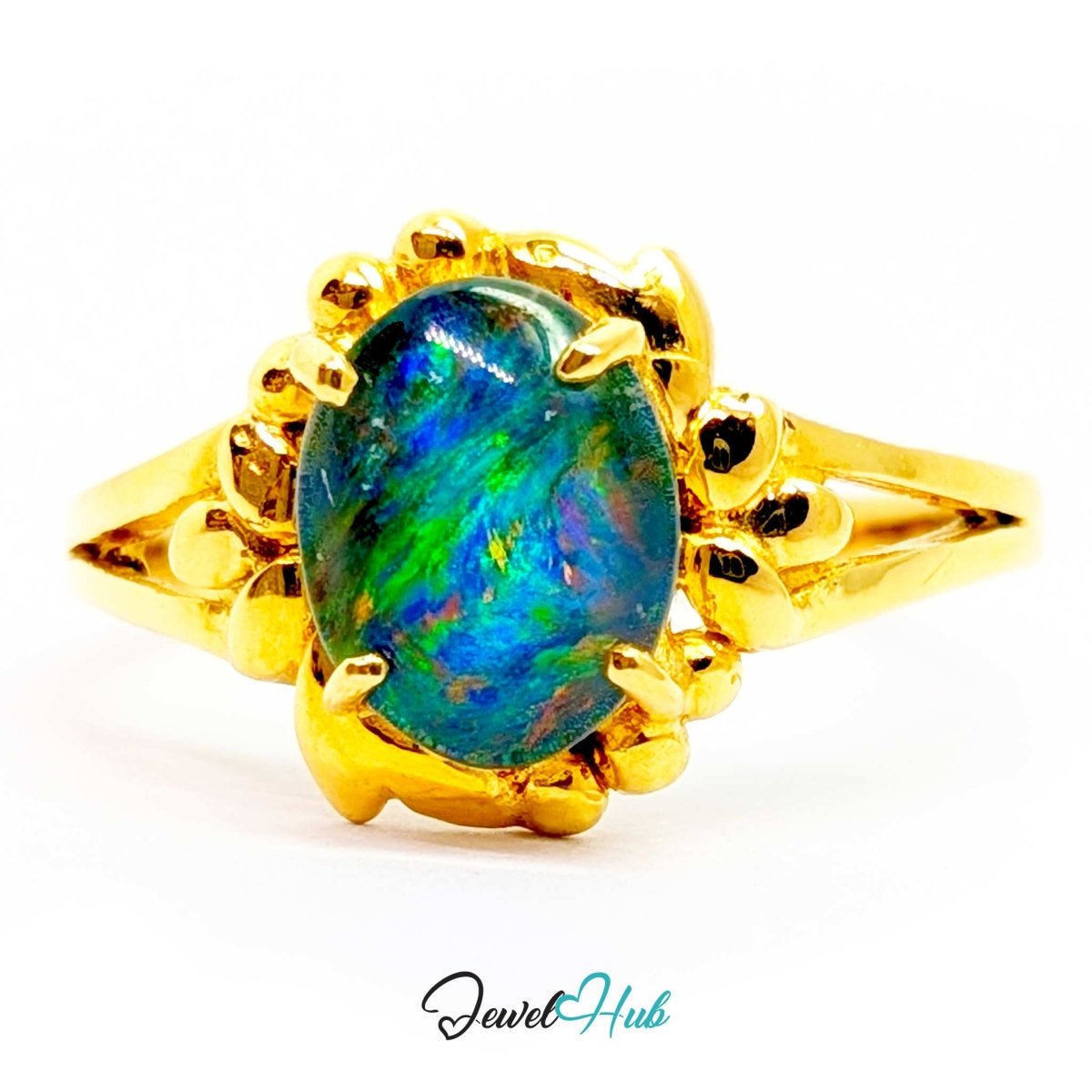 A 18k yellow gold ring featuring an oval-cut opal gemstone with vibrant blue, green, and purple iridescent play-of-color, set in a decorative claw-style gold frame on a white background.
