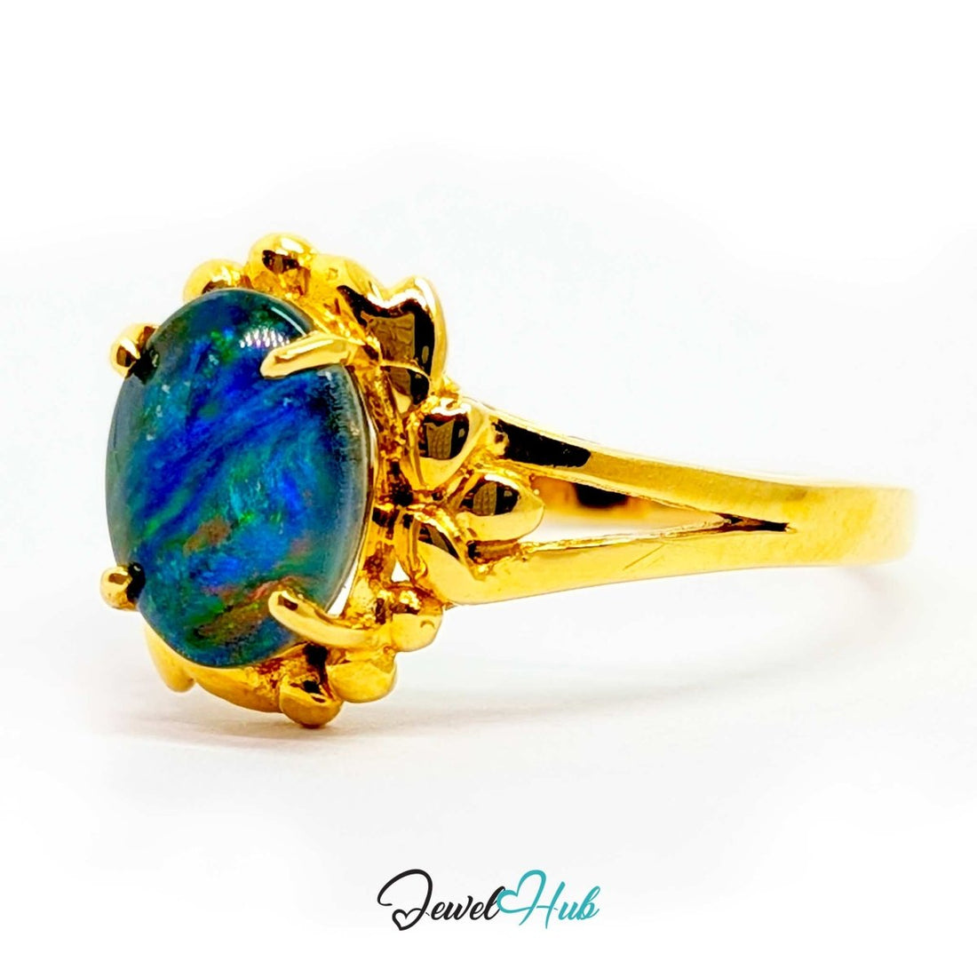 A yellow 18k gold ring featuring an oval-cut iridescent opal gemstone with vibrant blue, green, and orange flashes, set in a decorative claw-style gold bezel on a white background.
