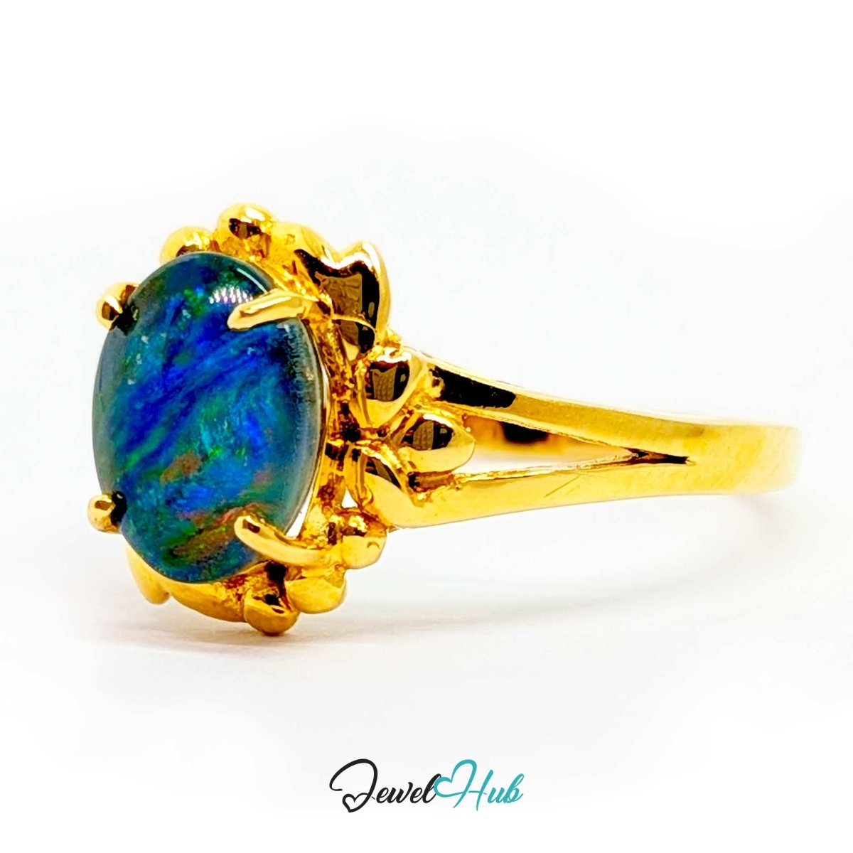 A yellow 18k gold ring featuring an oval-cut blue opal gemstone with vibrant green and orange flashes, set in a decorative floral crown prong setting on a white background.