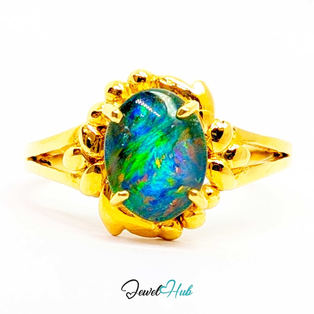 A yellow 18k gold ring featuring an oval-cut iridescent opal gemstone with vibrant blue, green, and orange flashes, set in a decorative claw-style gold bezel on a white background.