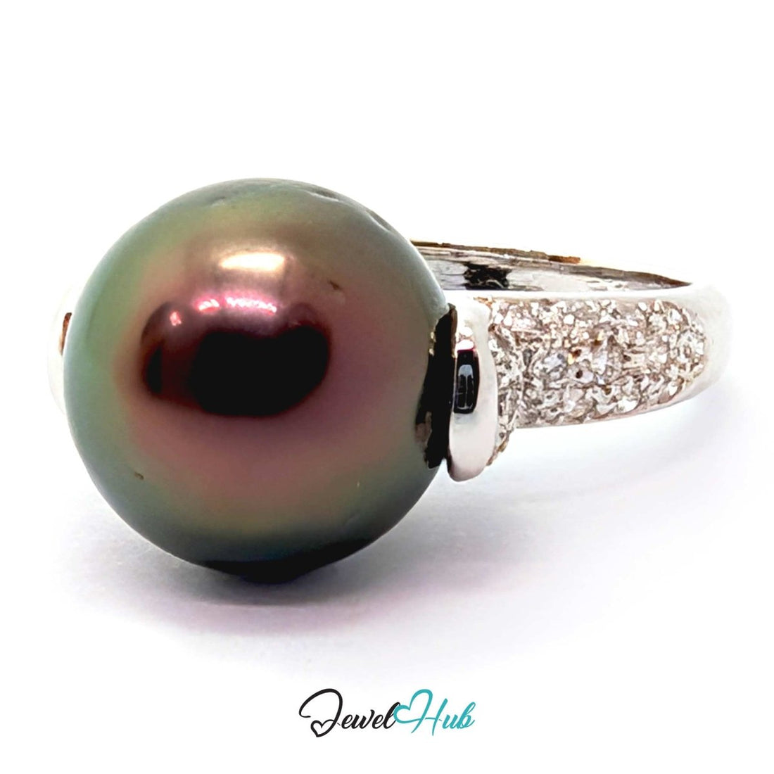 A 18k white gold featuring a large, round, dark green-black Tahitian pearl with iridescent pinkish-purple reflections, accented by pavé-set clear stones on the band, shown on a white background with a 'JewelHub' watermark.