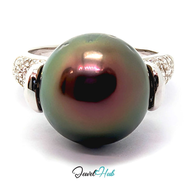 A 18k white gold featuring a large, round, dark green-black Tahitian pearl with iridescent pinkish-purple reflections, accented by pavé-set clear stones on the band, shown on a white background with a 'JewelHub' watermark.