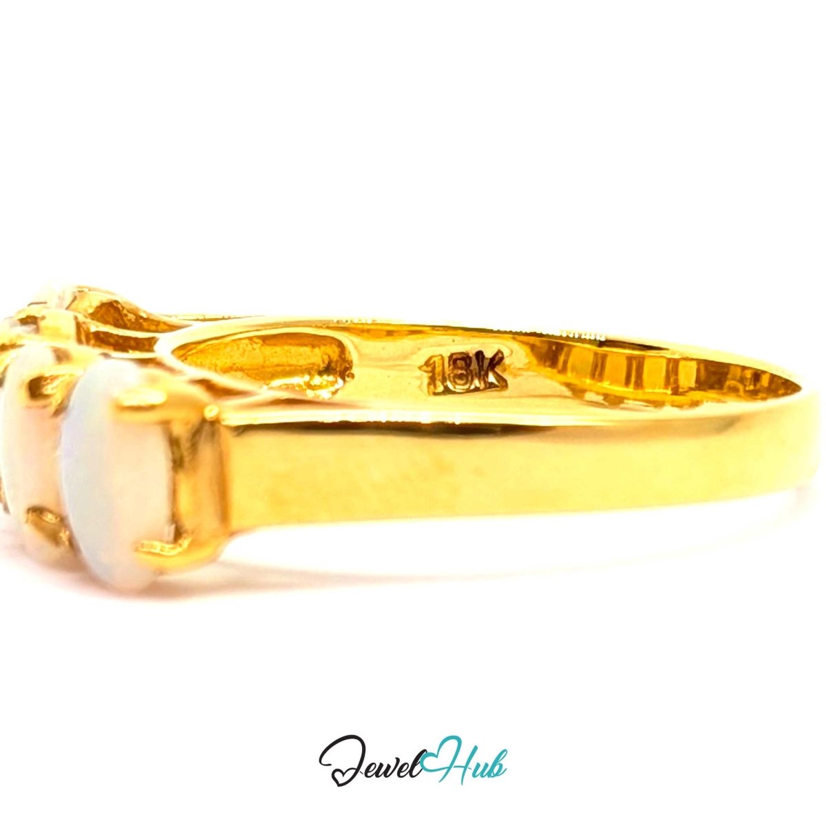 A close-up side view of a 18k yellow gold ring with a white opal stone, showing a '18K' gold purity stamp inside the band, on a white background with a 'JewelHub' watermark.
