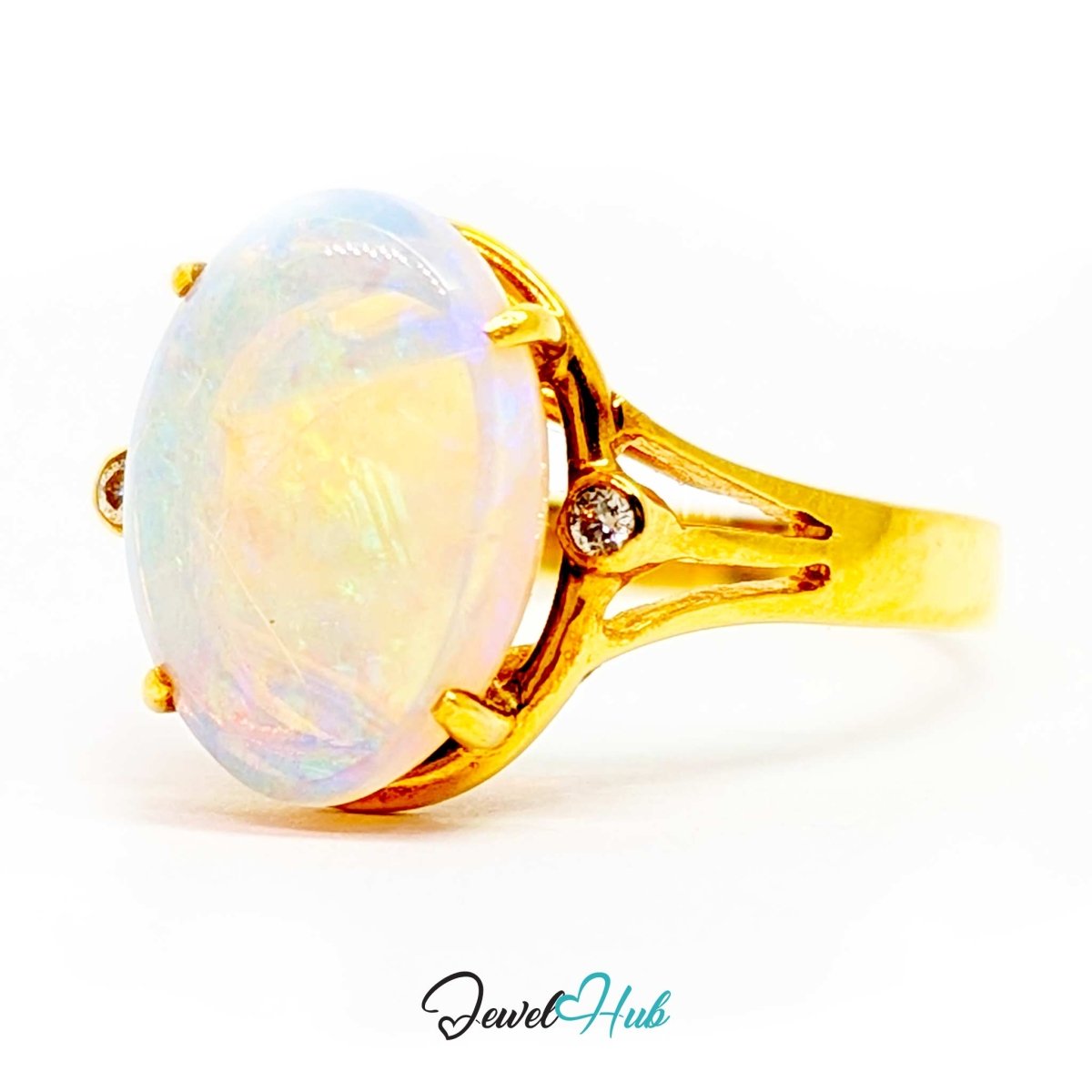 A 18k yellow gold ring featuring a large oval cabochon opal with iridescent white and pastel colors, accented by a small round diamond on the band, set against a plain white background.