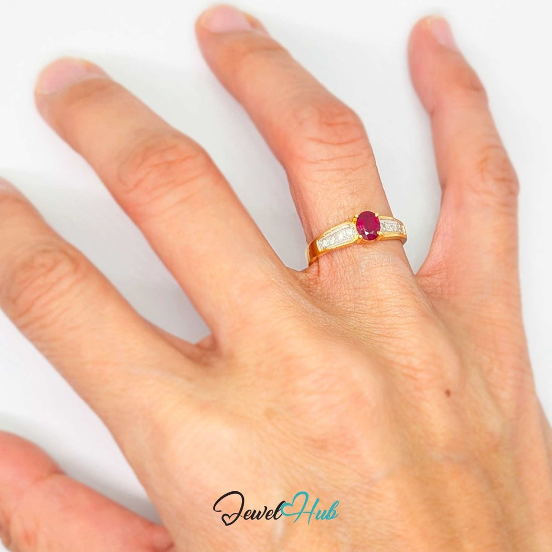 A yellow 14k gold ring featuring a prominent oval-cut deep pinkish-red center stone, flanked by rows of small clear stones on a white background.