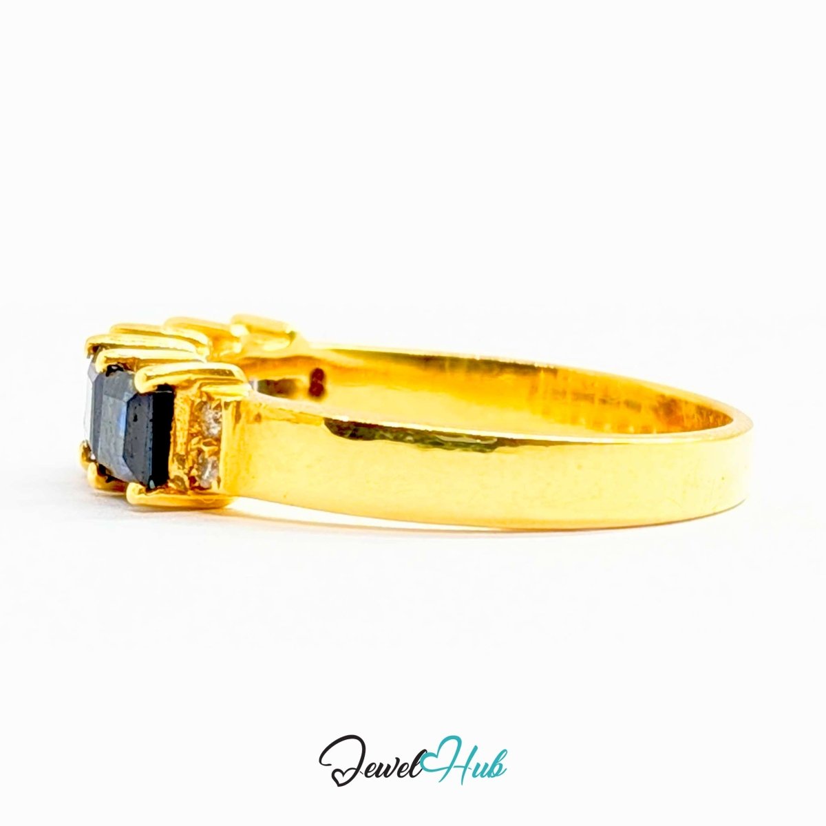 A yellow 18k gold ring featuring a rectangular dark blue sapphire center stone and small clear accent stones on either side, shown against a plain white background with a 'JewelHub' watermark at the bottom.