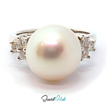 A white freshwater pearl ring with a white gold band accented by small clear gemstones on each side, shown on a white background with a 'JewelHub' watermark at the bottom.
