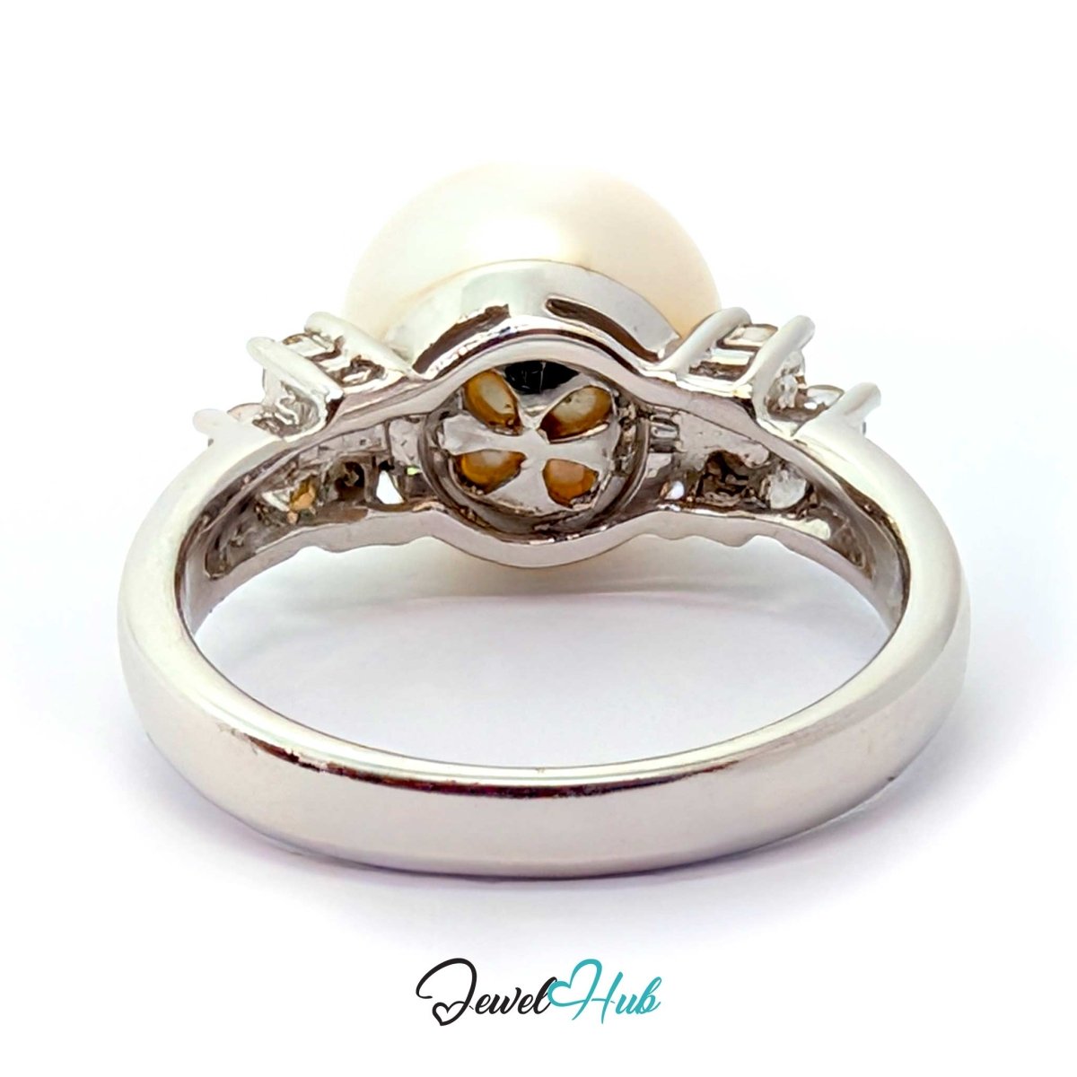 A white gold ring featuring a large round white pearl and a central floral cluster of small amber-colored stones, shown on a white background with a JewelryHub watermark.