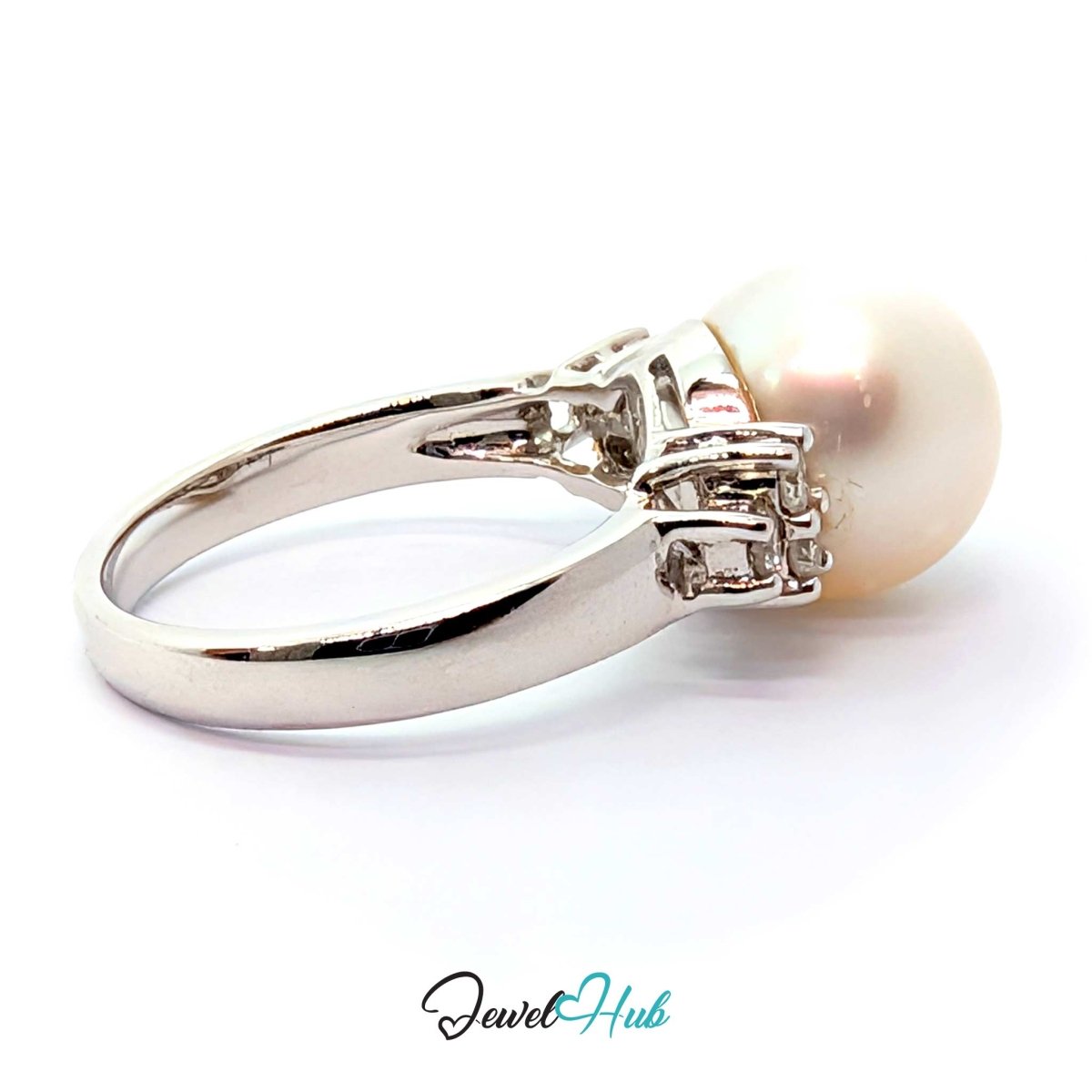 A white gold ring featuring a large, round, off-white pearl set in a polished silver band with small accent stones, shown on a white background with a 'JewelHub' watermark.